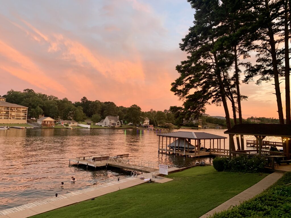 Sunset at the lake, boats docks and trees. Kids swimming