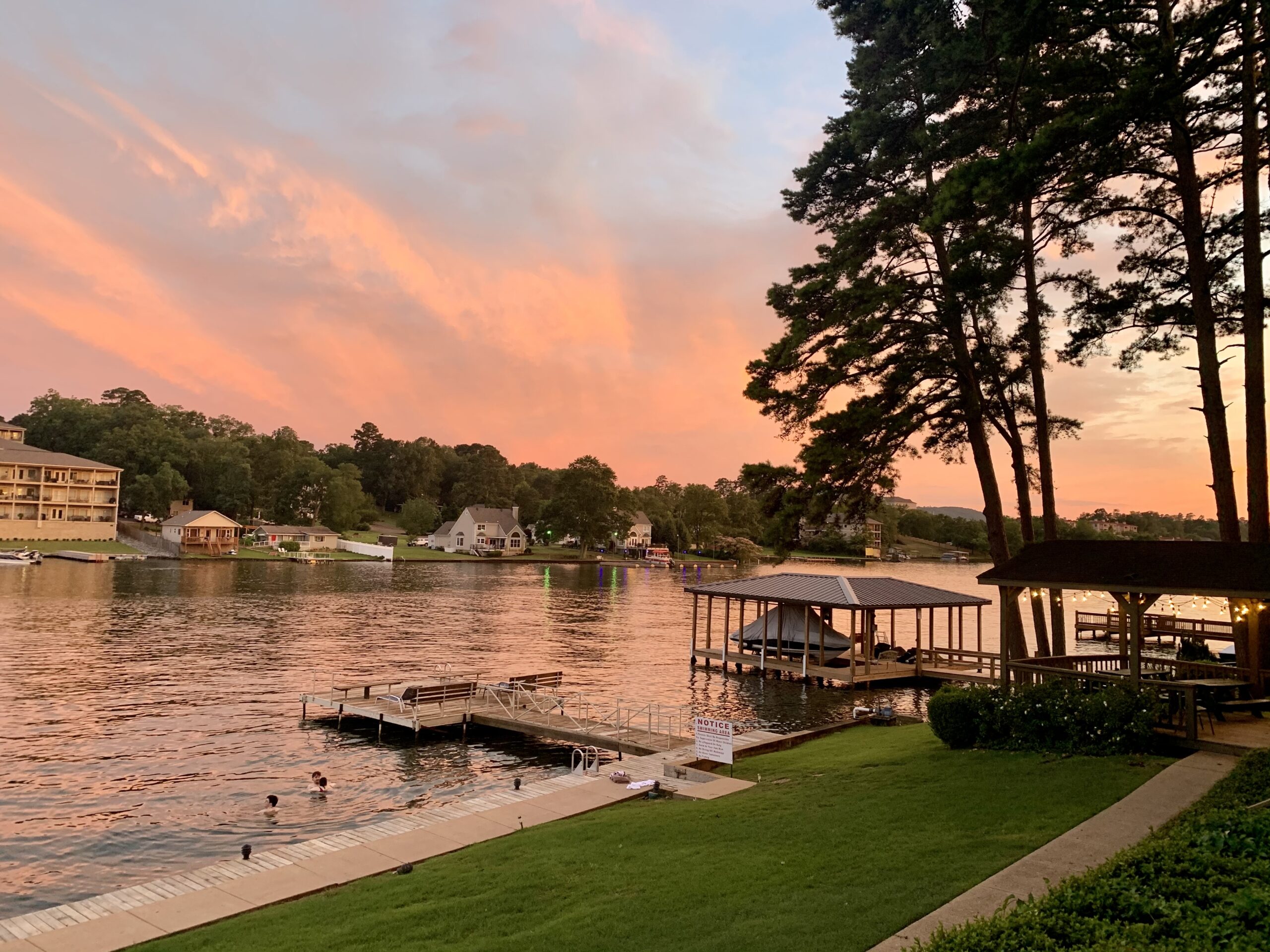 Sunset at the lake, boats docks and trees. Kids swimming